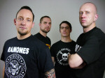 Volbeat-bändin promokuva, jossa vaaleanharmaata taustaa vasten seisoo neljä miestä. Jokaisella lyhyet hiukset ja mustat t-paidat yllään.