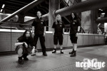Needleye-bändin promokuva, jossa miehet seisovat jossakin autohallissa tms. Kuva on mustavalkoinen ja sen oikeassa alakulmassa bändin logo.