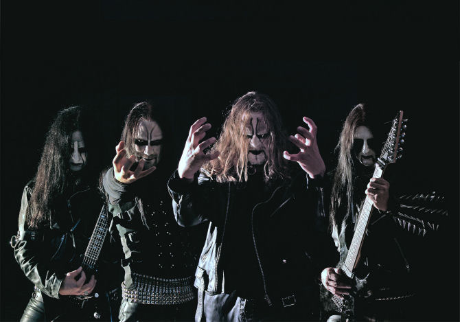 Valokuvassa Dark Funeral, jonka jäseniä kuvassa neljä kappaletta. He seisovat mustaa taustaa vasten rivissä. Kaikilla pitkät hiukset, mustat vaatteet, laitimmaisilla kitarat kourissaan. Miehillä corpse maskit kasvoilla ja niittirannekkeita sekä -vöitä yllään