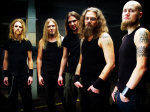 Mokoma-bändin promokuva, jossa viisi miestä seisoo lyhythihaisissa paidoissa. Miehillä mustat vaatteet ja paljon karvoja.