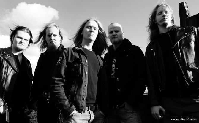 Harmaasävyinen promovalokuva Fleshkraft-bändin jäsenistä. Kuvassa yhteensä viisi miestä, joilla mustat vaatteet ja joilla keskimmäistä lukuunottamatta pitkät hiukset. He seisovat ulkona pilvisen taivaan alla.
