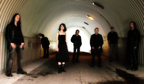 Silentium-bändin jäsenet, eli kuusi miestä ja yksi nainen, seisovat tunnelin suuaukon äärellä. Kaikilla mustat vaatteet.