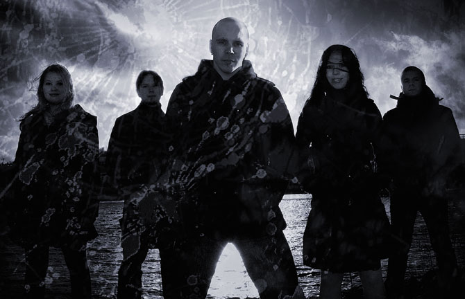 Promovalokuva Dark The Sunsista. Bändiin kuuluu viisi ihmistä, joista kaksi naisia ja loput miehiä. He seisovat meren rannalla mustiin vaatteisiin pukeutuneina. He ovat rivissä sinisen taivaan alla. Osa naisista nauravaisia.