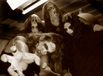 Marduk-bändin jäsenet corpse-maskit kasvoilla kouristelevat. Miehillä pitkät hiukset. Kuva on harmahtava.