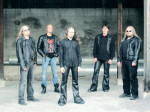 Crystalic-bändin jäsenet seisovat harmahtavaa seinää vasten. Kuvassa viisi miestä, joista kolmella on pitkät hiukset.
