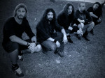 Eldritch-bändin jäsenet sinisävyisessä kuvassa. Miehet istuvat rivissä kyykyssä nurmikolla. Osalla miehistä pitkät hiukset.