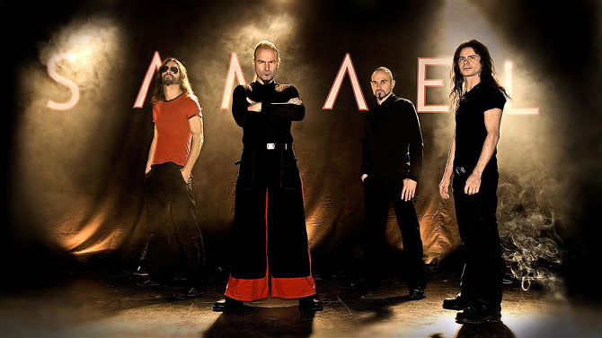 Valokuva neljästä miehestä, jotka seisovat tummaa taustakangasta vasten, johon kirjoitettu Samael tikkukirjaimin. Kuvan jäsenet ovat pukeutuneet pääosin mustiin vaatteisiin, mutta osalla tehostevärinä punaista paidassa ja housuissa.