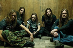 Children Of Bodom -bändin jäsenet istuvat puuseinän edessä lattiolla. Kuvassa myös Alexi Laiho. Miehillä (5 kpl) on pitkät hiukset.