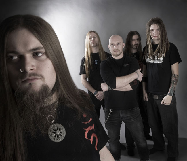 Valokuva mustiin pukeutuneista hevimiehistä, jotka seisovat harmaata taustaa vasten. Miehistä vasemmalla pitkähiuksinen heppu, jonka takana kalju mies ja muita pitkälettisiä metallimiehiä. Heitä kuvassa viisi kappaletta.