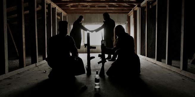 Kuvassa promootiokäyttöön tarkoitettu valokuva venäjänkielistä doom metallia soittavasta KYPCK-yhtyeestä, jonka keulahahmona toimiva Erkki Seppänen on venäjää suluvasti solkottava suomalaismuusikko. Tämä kuvassa näkyvä metallibändi nauhoittaa nyt uutta albumia julkaistavaksi jossain vaiheessa vuotta 2010 vielä toistaiseksi tuntemattoman levymerkin kautta, mutta kiekon julkaisemiseen osallistunee ainakin Century Media Recordsin väki. KYPCK-bändin jäsenet matalakattoisessa varastomaisessa tilassa, jossa puisten häkkiovien keskellä olevassa käytävässä neljä miestä vastavaloa vasten. Kuvassa keskimmäisenä konetuliaseita ja pari miestä taaempana kättelemässä toisiaan.