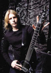 Kitaristi Christopher Amott seisoo seinää vasten kitara käsissään. Miehellä musta pitkähihainen paita ja päässä puolipitkät vaaleat hiukset.