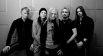 Mustavalkoinen valokuva, jossa Soulrelic-bändin jäsenet seisovat rivissä valkoista tiiliseinää vasten. Kuvassa viisi miestä, joista kolmella vaaleat hiukset, kahdella miehistä pitkät hiukset.