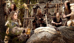Turisas-bändin jäsenet poseeraavat viikinkikylässä. Miehiä kuvassa viisi kappaletta, joista jokainen pukeutunut viikinkiasuihin, kuten turkiksiin ja alkeellisiin vaatteisiin.