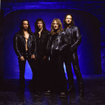 Gamma Ray -bändin miehet, neljä miestä, seisovat tummassa huoneessa, jonka taaimmainen seinä on tummansininen. Miehillä yllään nahkavaatteet, mustat sellaiset.
