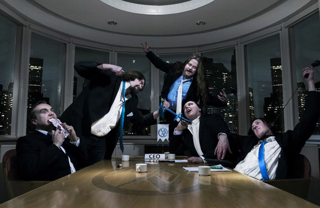 Ryhmäkuva MindMirror-bändin kokoonpanosta pöydän äärellä. Miehet pukeutuneet tummiin pukuihin ja jokaisella sininen kravatti kaulassa.