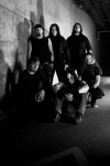 Pain Confessor -bändin mustavalkea promokuva, jossa miehet ryhmittyneet kiviseinän viereen. Kuvassa kuusi miestä, joista kolme seisoo ja kolme istuu.