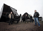 The Scourger -bändin promokuva, jonka otti Tanja Ahtila. Bändin jäsenet seisovat suurten kaivinkoneiden kauhojen ääressä.